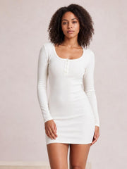 Model poses in a white long sleeve bodycon mini dress with a scoop neckline, buttoned front placket, and fitted stretch silhouette.