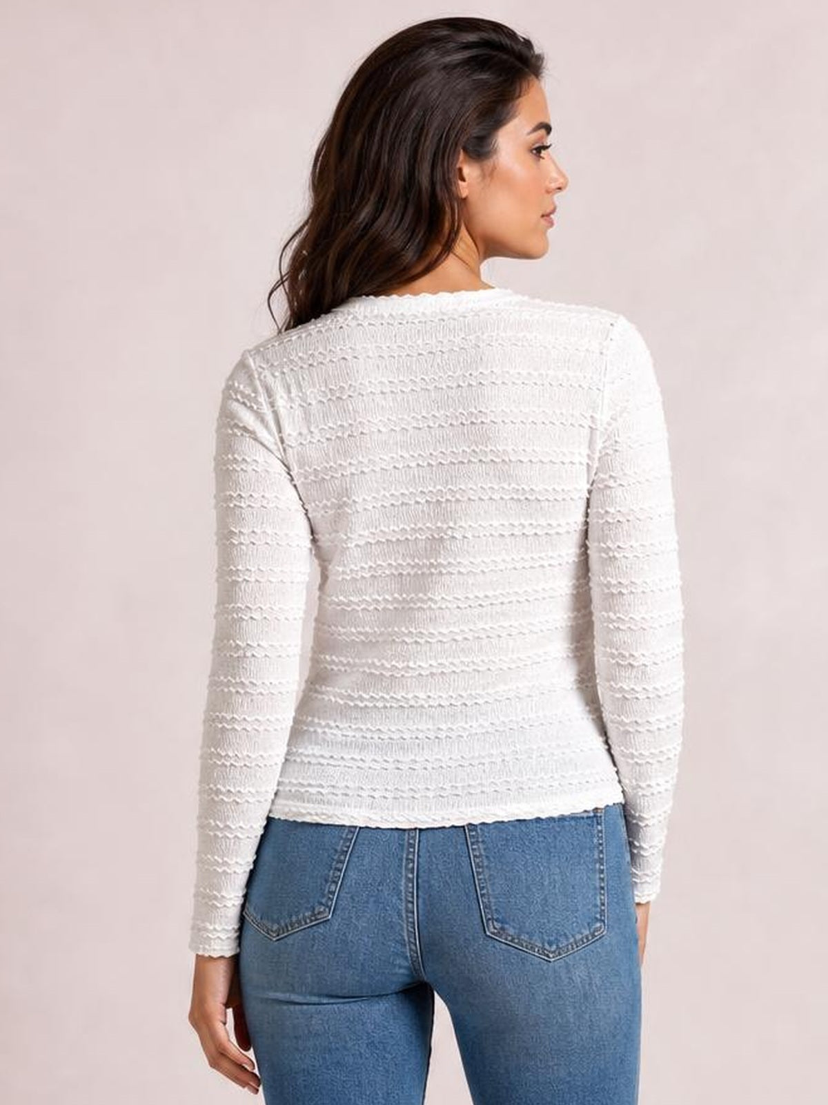 Model shown from the back in a white long sleeve jacquard slim top with textured horizontal patterning, fitted silhouette, and a slightly turned pose.