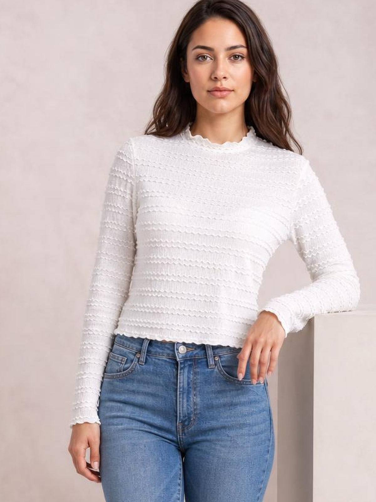 A model wears a white long-sleeve jacquard slim top with a textured horizontal pattern, fitted silhouette, and softly scalloped neckline and cuffs.