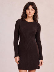 Model wears a dark brown long sleeve ribbed knit dress with a round neckline, fitted waist, stretchy textured construction, and short straight skirt.