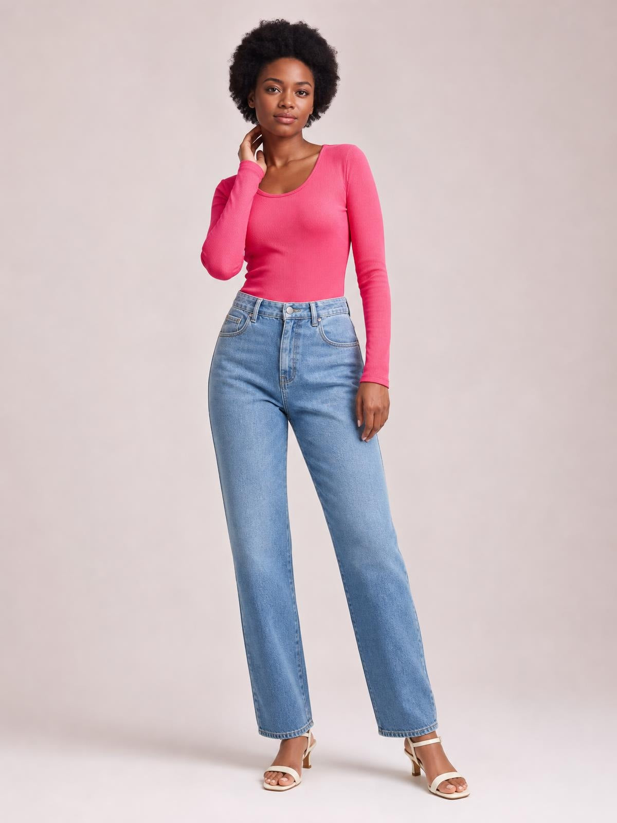 A model poses with one hand at her neck, wearing a bright pink, fitted long sleeve scoop neck T-shirt with a clean, basic silhouette.
