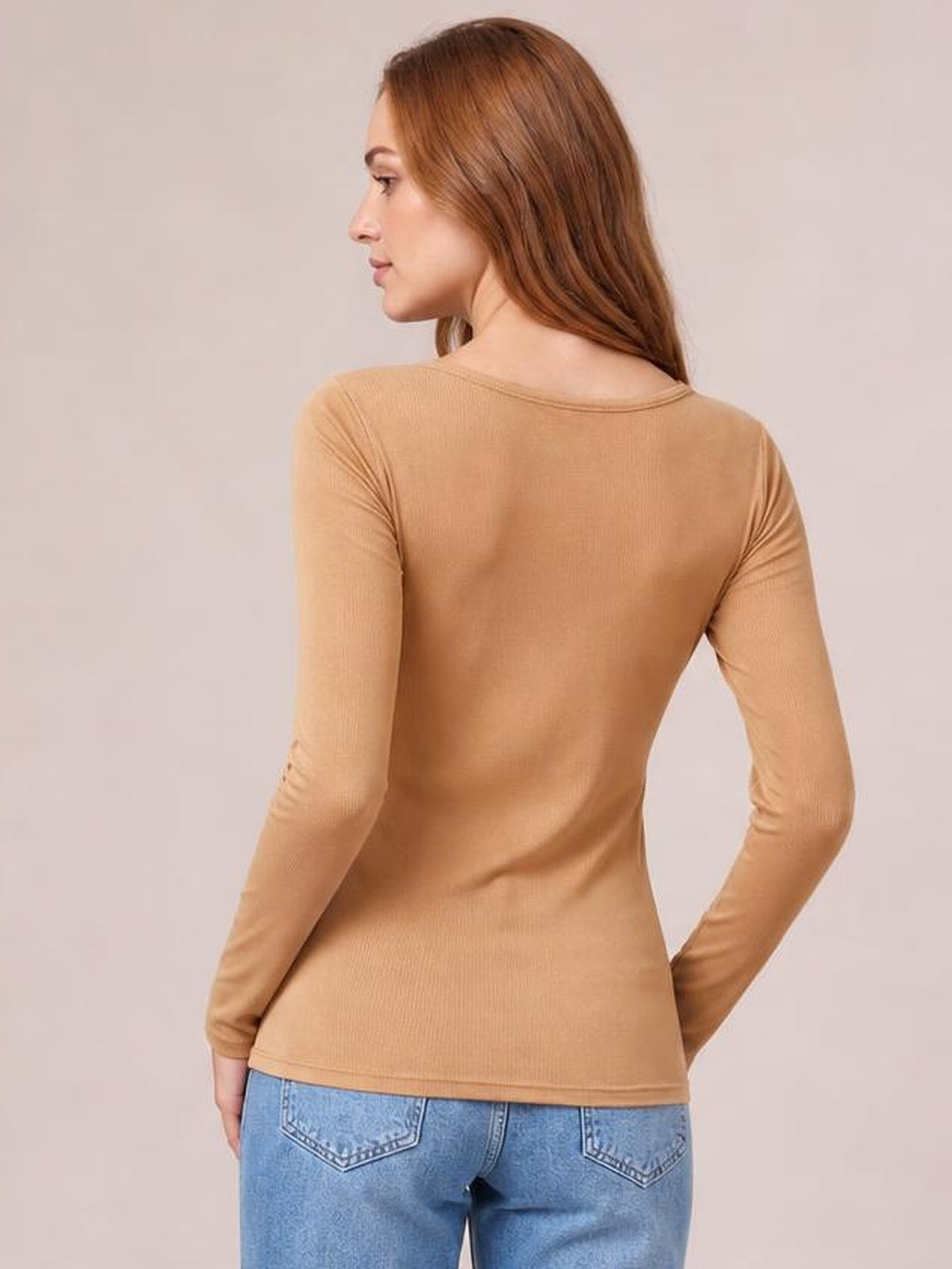 A model poses in a tan long sleeve scoop neck T-shirt, shown from behind with a fitted silhouette, stretch construction, and neatly finished hem.