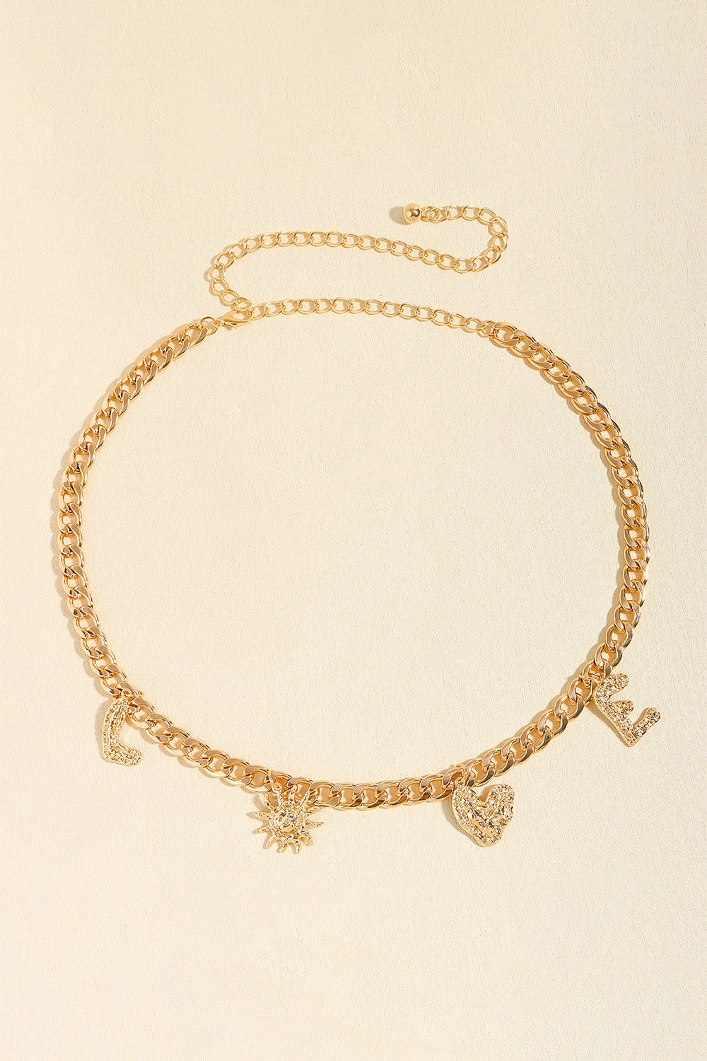 Gold alloy chain belt with a slim linked silhouette, adjustable loop closure, and dangling letter and symbolic charms for playful movement.