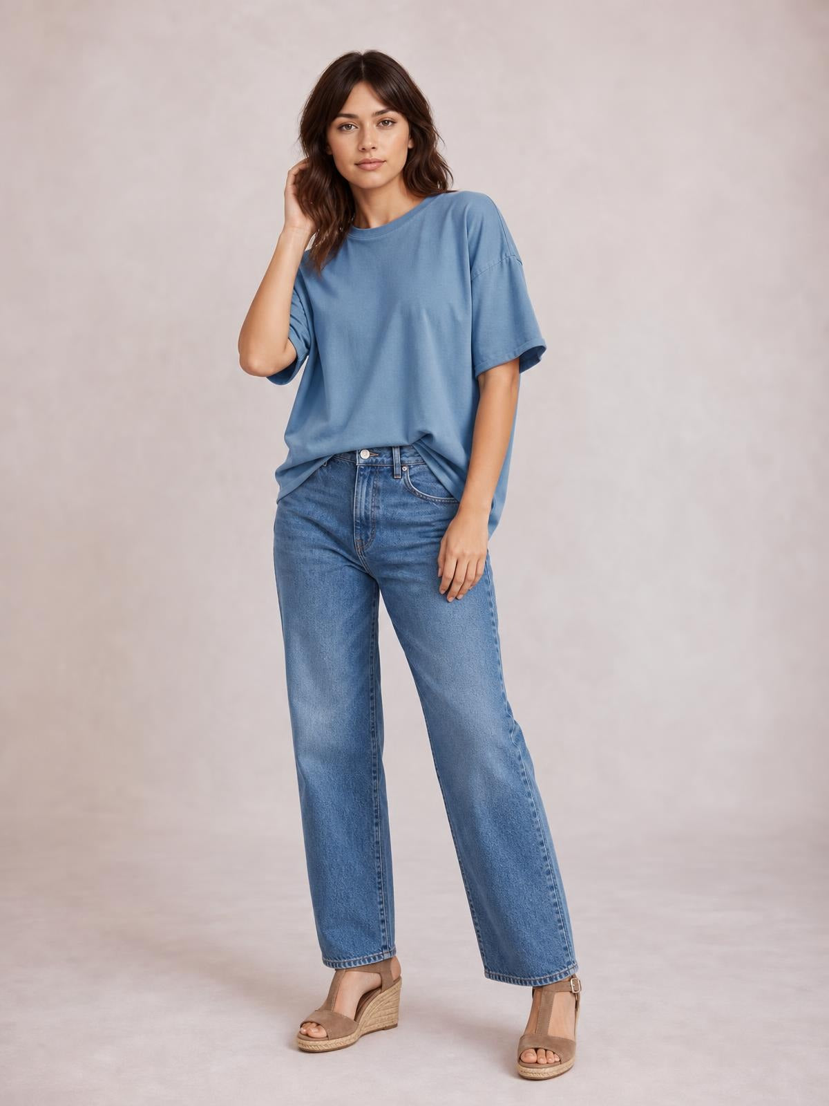 Model poses in a blue exposed seam round neck half sleeve T-shirt with a relaxed, oversized silhouette and dropped shoulder construction.