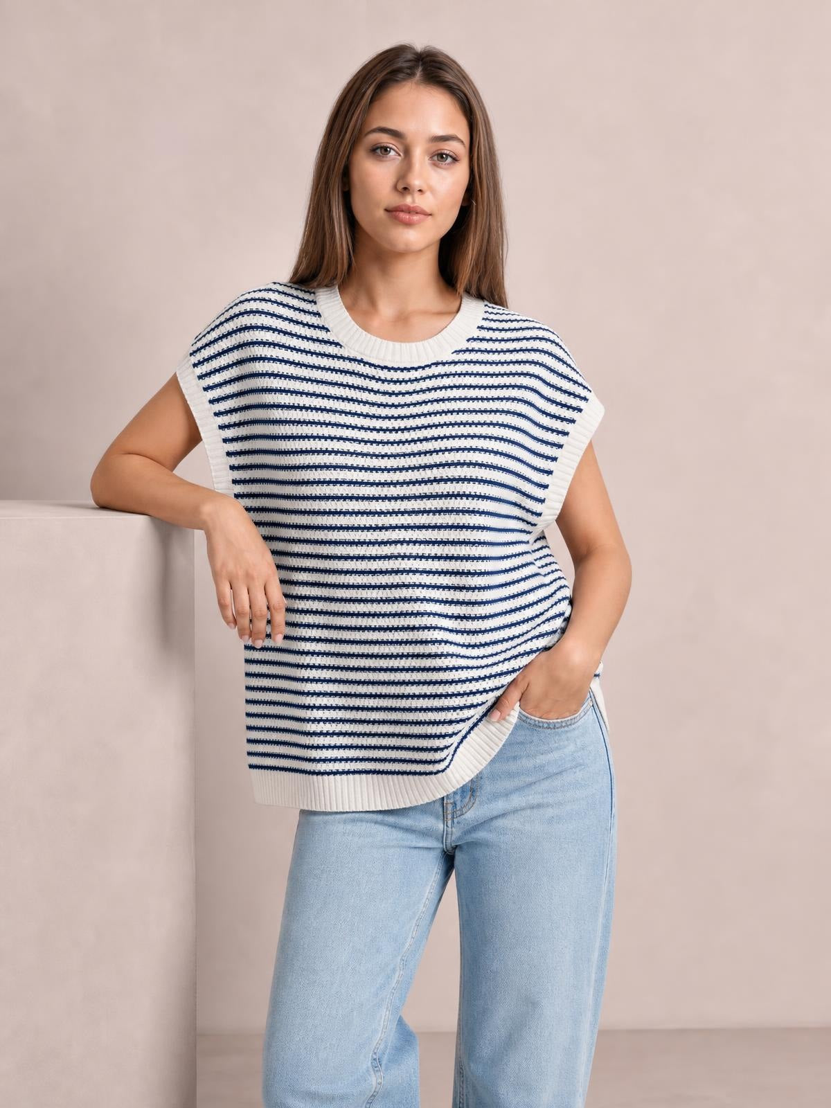 Model poses in a navy and white striped round-neck cap-sleeve sweater with ribbed trim and a relaxed silhouette, paired with light-wash jeans.