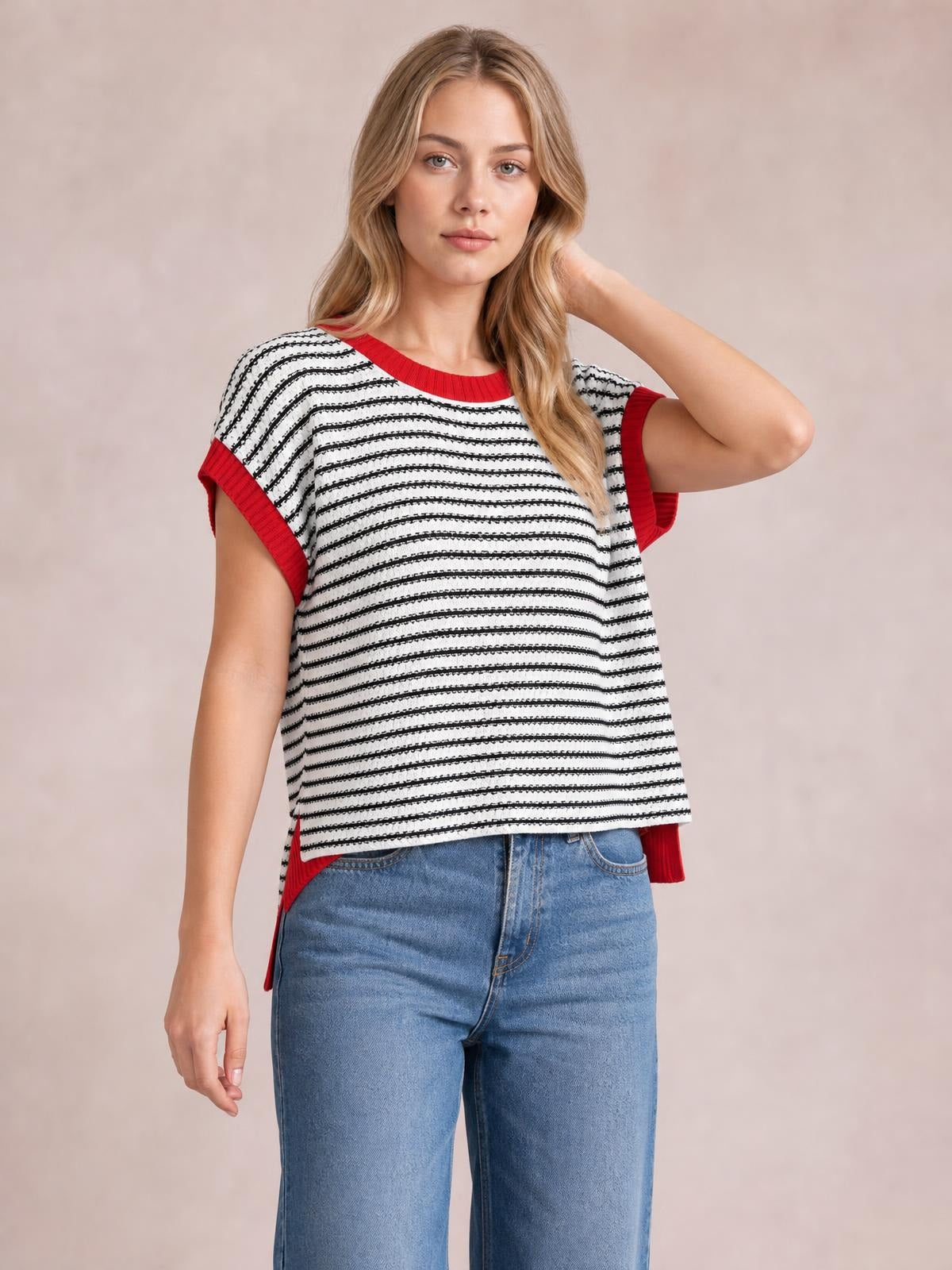 Model poses in a relaxed striped round-neck cap-sleeve sweater with black-and-white horizontal stripes, red ribbed trim, and a loose silhouette.