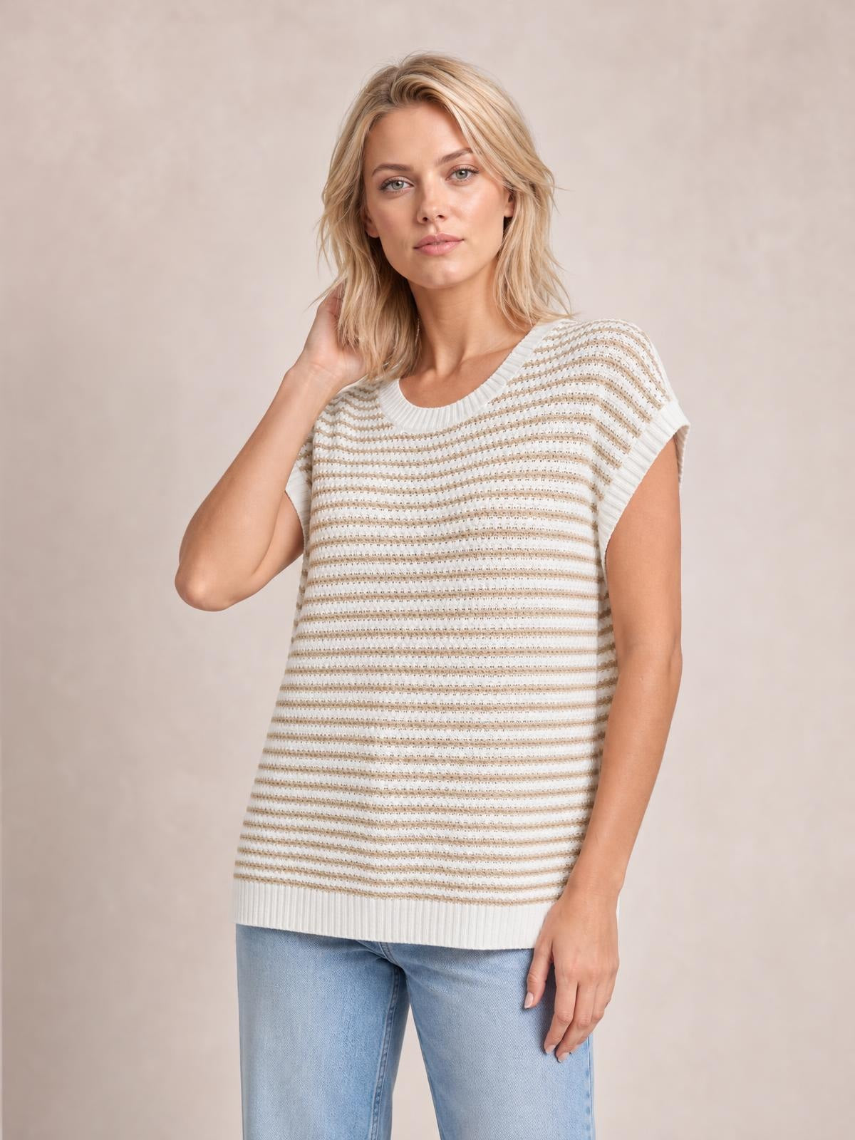 Model poses in a cream and beige striped round-neck sweater with ribbed cap sleeves, a relaxed straight silhouette, and ribbed neckline and hem.