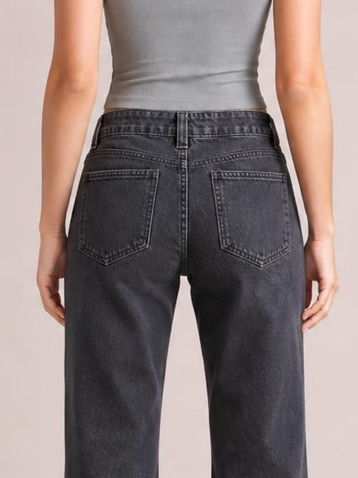 A model stands with hands at her sides, showing dark charcoal low-rise flare-leg jeans with belt loops, a fitted seat, and two stitched back pockets.