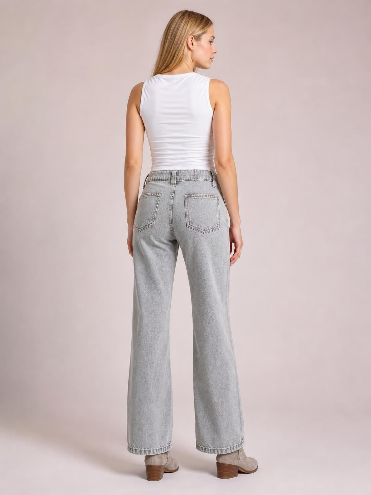 A woman poses from behind in light gray low rise flare leg jeans with a fitted seat, belt loops, and two back patch pockets.