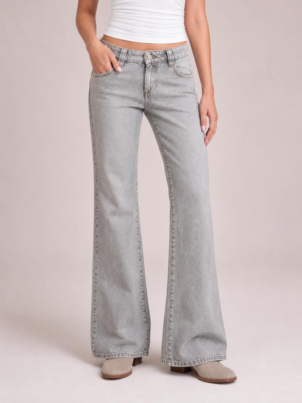 Model wearing light gray low-rise flare leg jeans with front pockets, belt loops, button closure, and a full-length wide-leg silhouette.