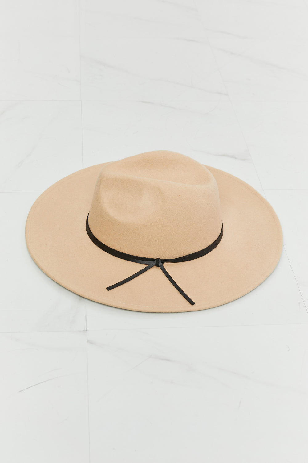 Beige fedora hat with a softly structured crown, generous 3.5-inch brim, and contrasting black band finished with a tied detail.