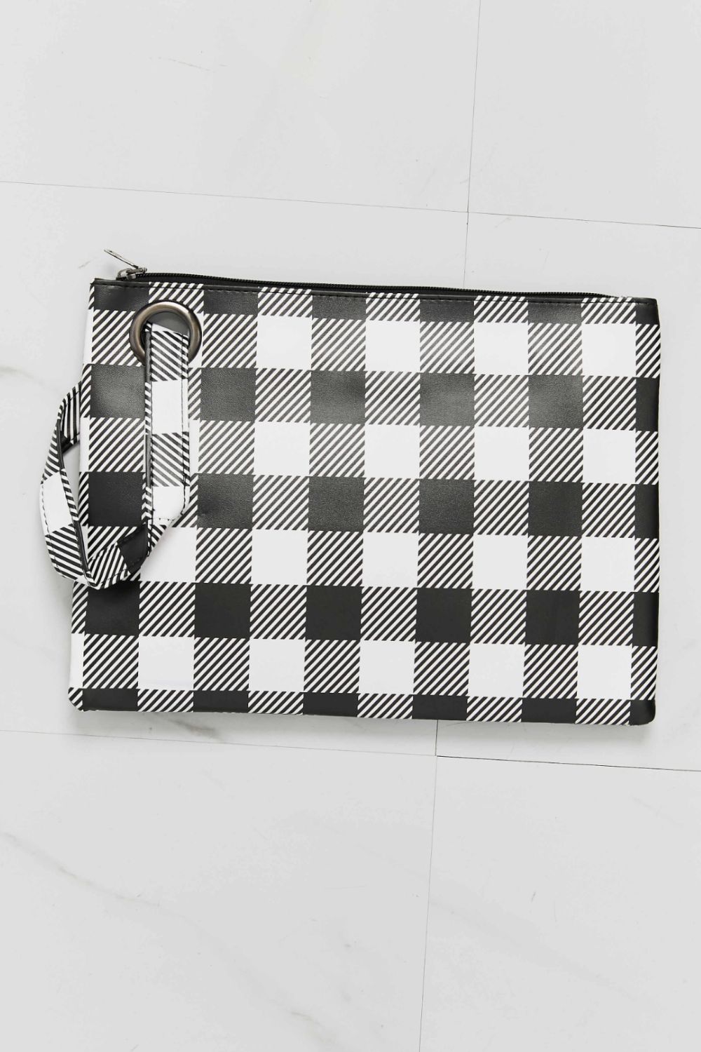 A medium rectangular PU leather wristlet features a bold black-and-white checkered print, top zip closure, and attached strap for hand or wrist carry.