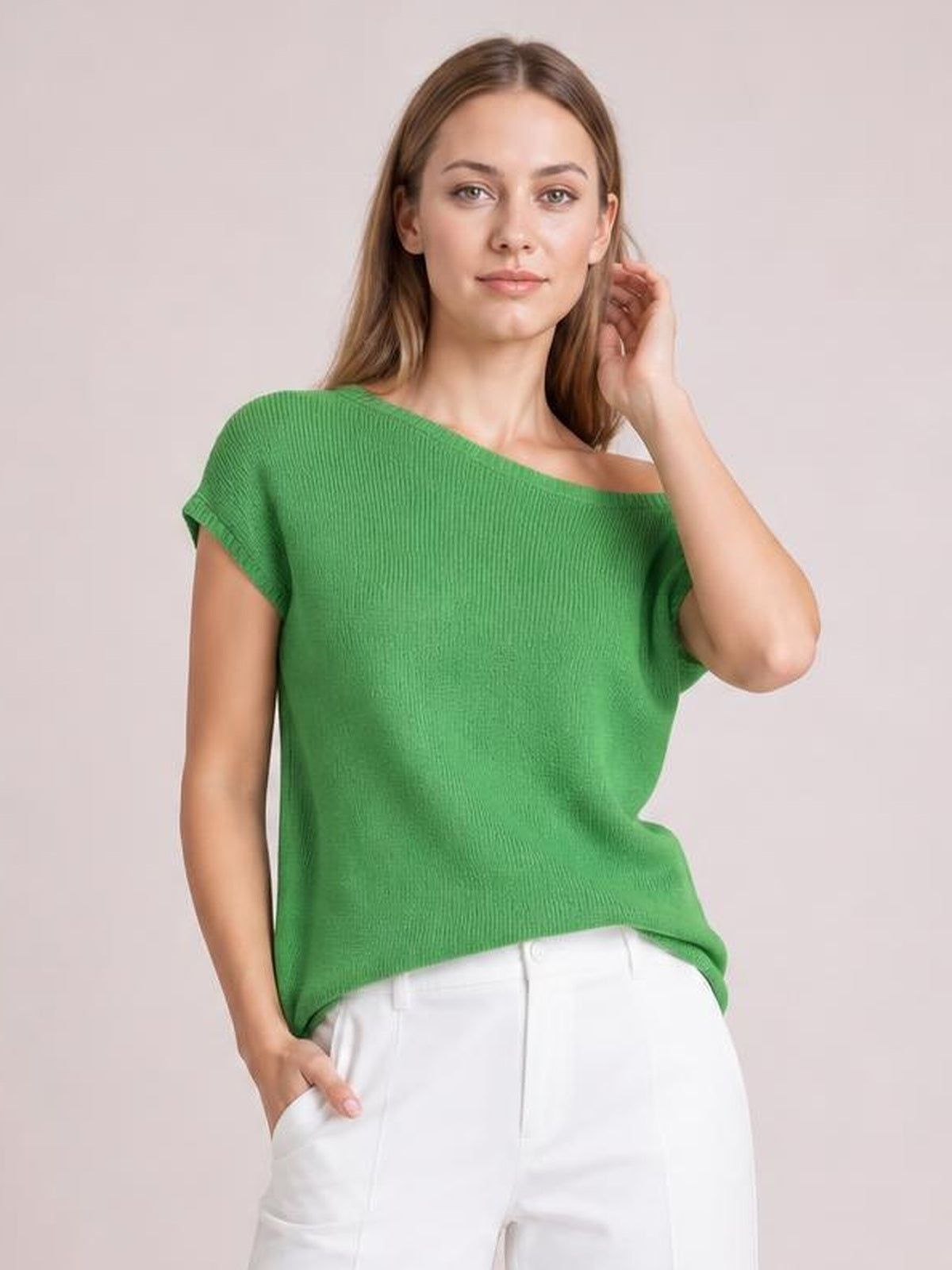 Model wearing a green boat neck short sleeve knit top with a relaxed silhouette and ribbed construction, posing with one hand in her pocket.