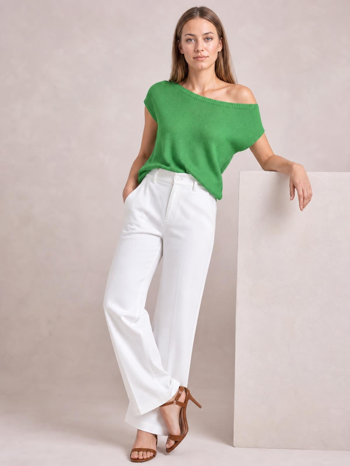 A model poses in a green boat neck short sleeve knit top with a relaxed, draped silhouette and wide neckline falling slightly off one shoulder.