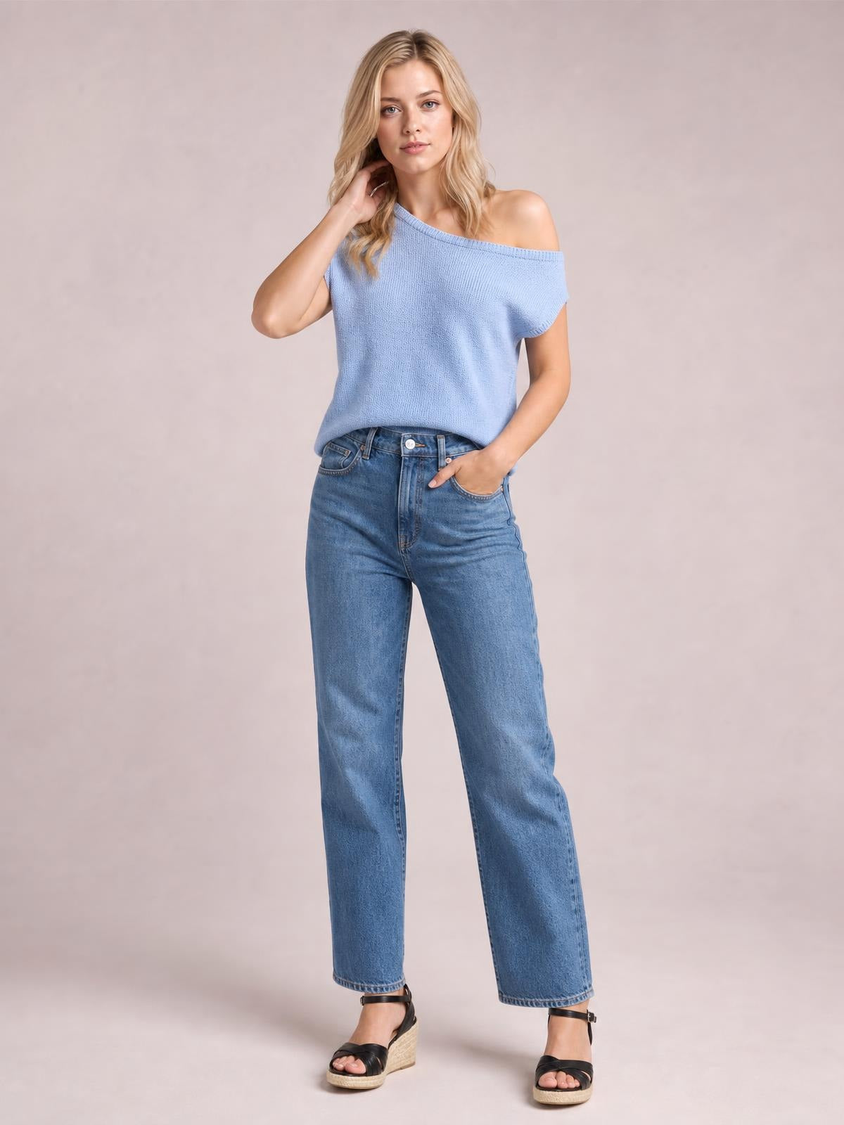 Model poses in a light blue boat neck short sleeve knit top with a relaxed, slightly off-shoulder silhouette and ribbed neckline.
