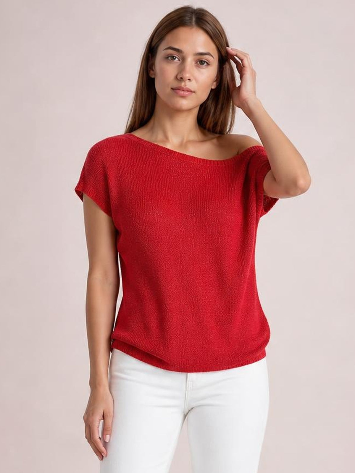 Model poses with one hand in her hair while wearing a red boat neck short sleeve knit top with a relaxed silhouette and ribbed edges.