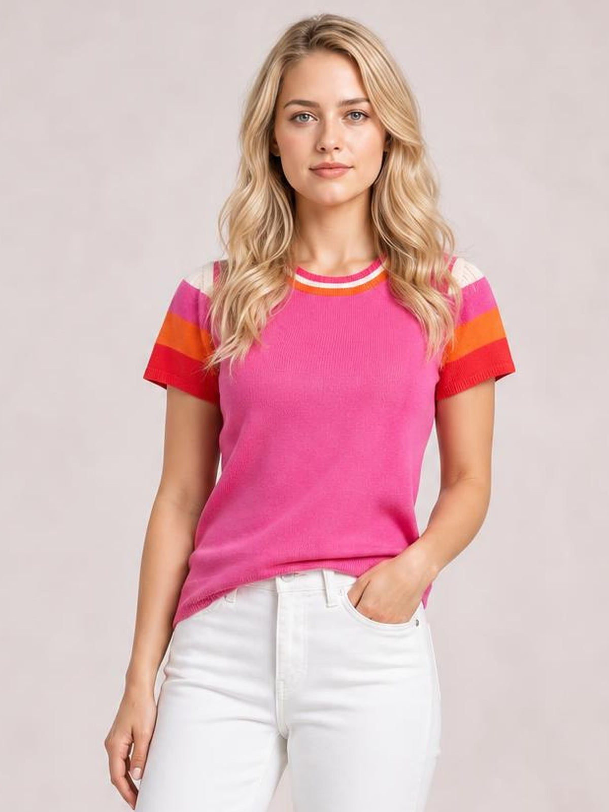 Model wearing a bright pink contrast knit top with a round neck, short sleeves, striped shoulder accents, and a relaxed straight silhouette.