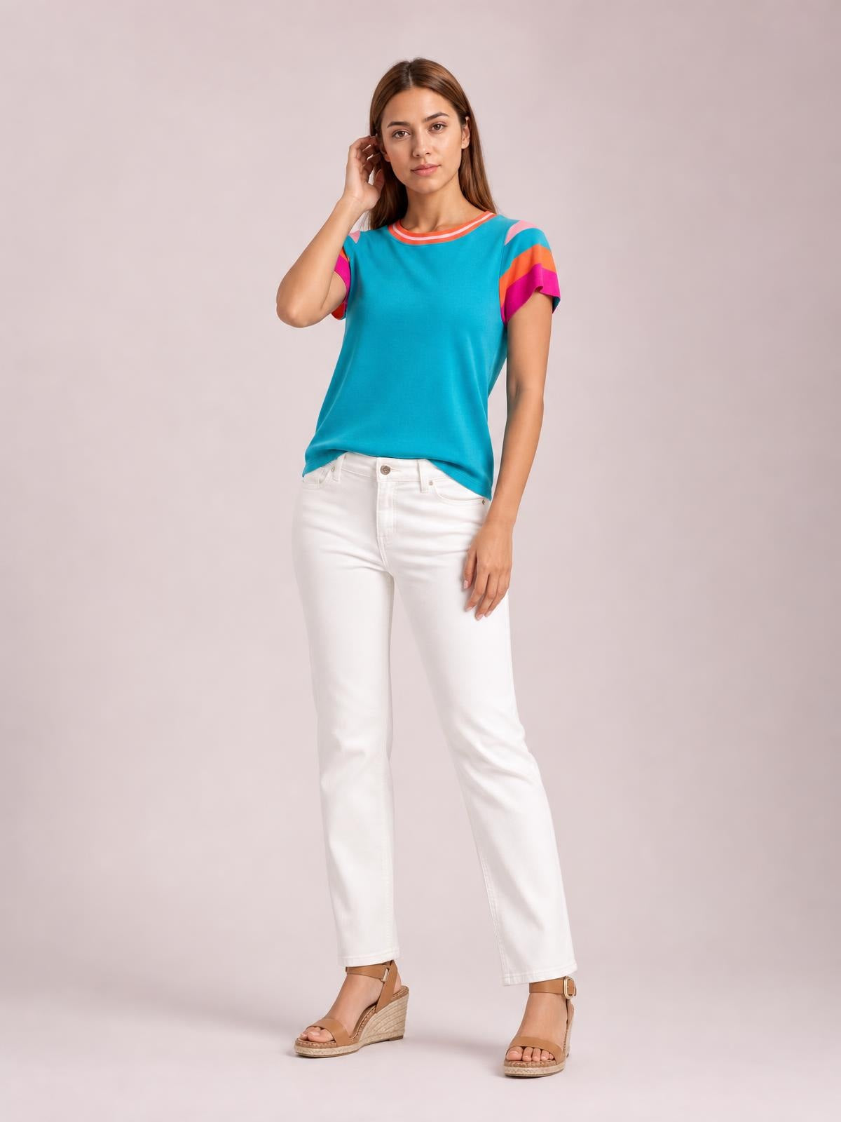 Model poses in a turquoise contrast round neck short sleeve knit top with colorful striped sleeve details and a relaxed straight silhouette.