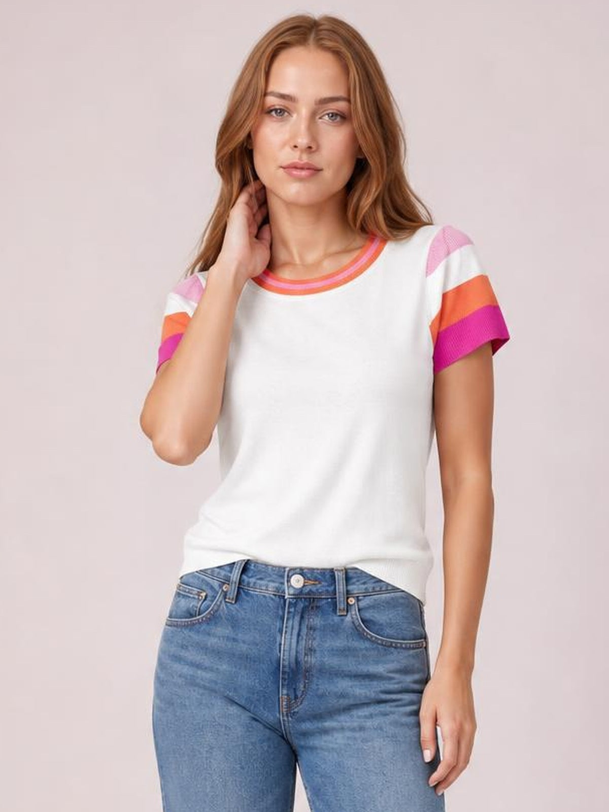 Model wearing a white contrast round neck short sleeve knit top with pink and orange striped sleeve bands, a relaxed straight silhouette, and ribbed neckline.