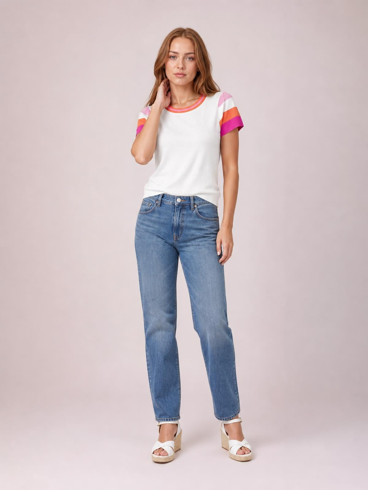 Model wearing a white contrast round neck short sleeve knit top with colorful striped trim, relaxed silhouette, and moderate stretch, posing with one hand near her neck.