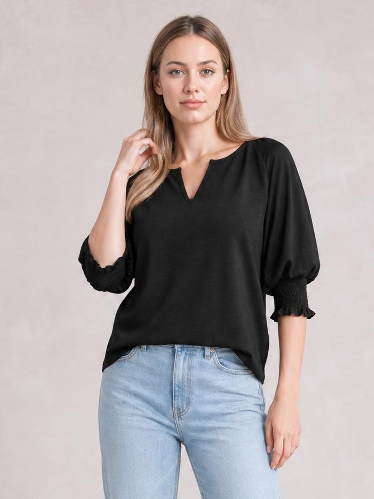 Model poses in a black heathered blouse with a notched neckline, loose lantern sleeves, frill-trimmed cuffs, and a relaxed silhouette.