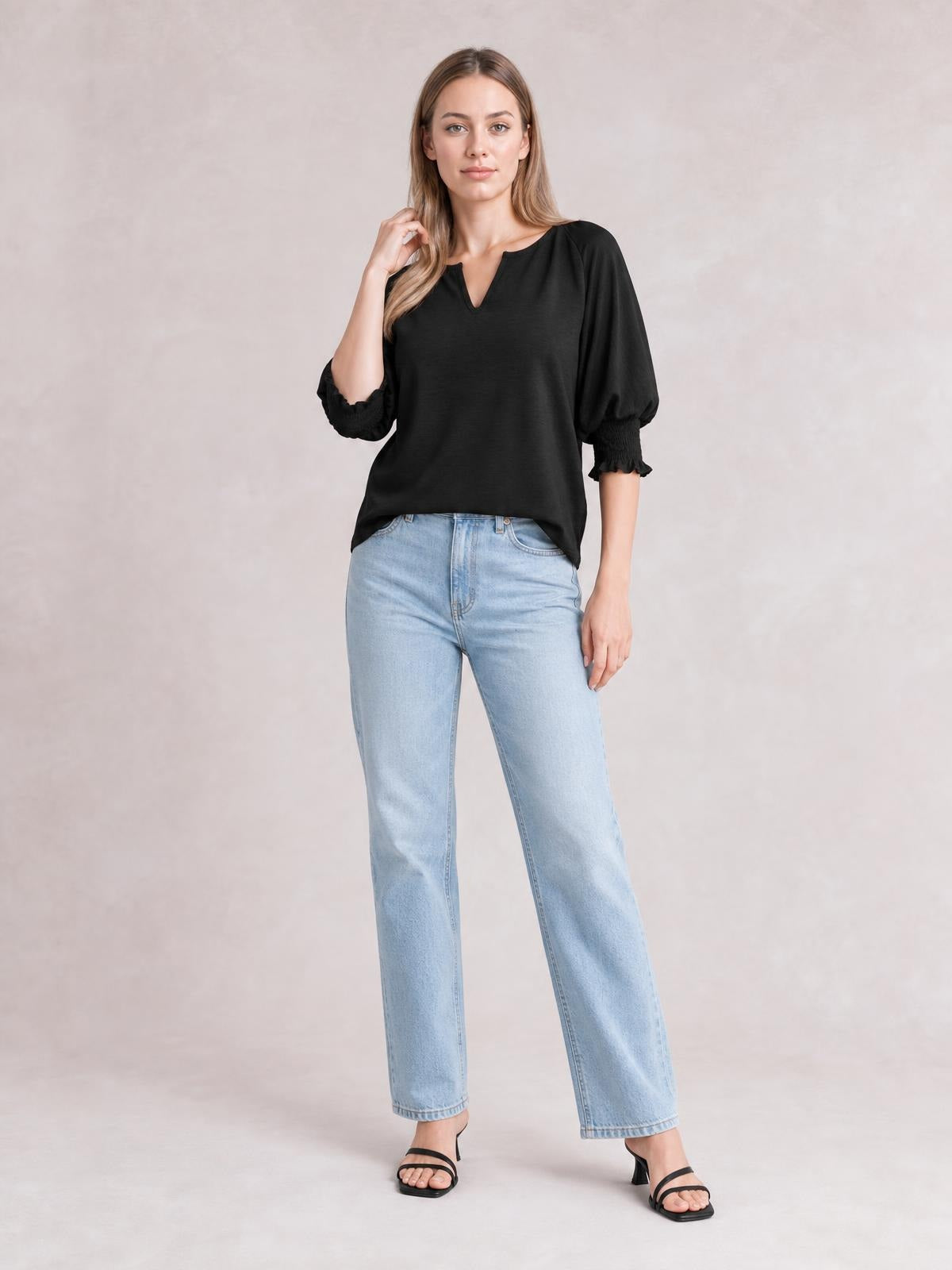 A model poses in a black heathered blouse with a notched neckline, relaxed silhouette, lantern sleeves, and frill-trimmed cuffs.