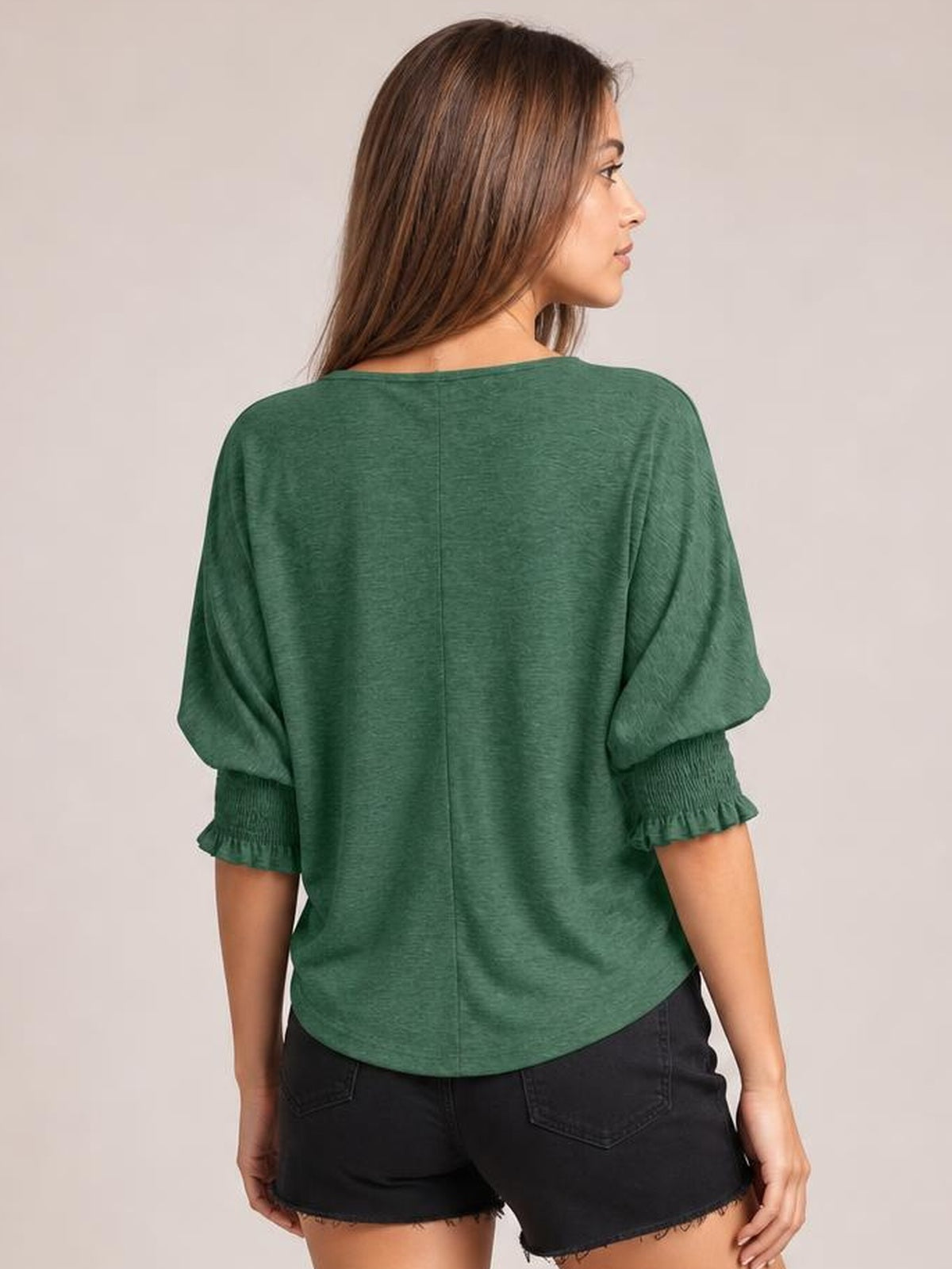 Model turned away displays a heathered green blouse with a relaxed silhouette, rounded neckline, lantern sleeves, gathered cuffs, and frill trim.