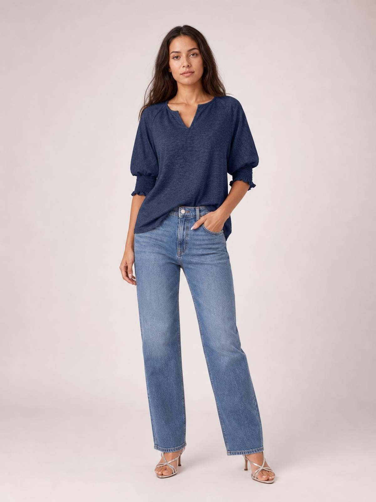 A model poses in a navy heathered blouse with a notched neckline, loose silhouette, lantern sleeves, and frill-trimmed cuffs.