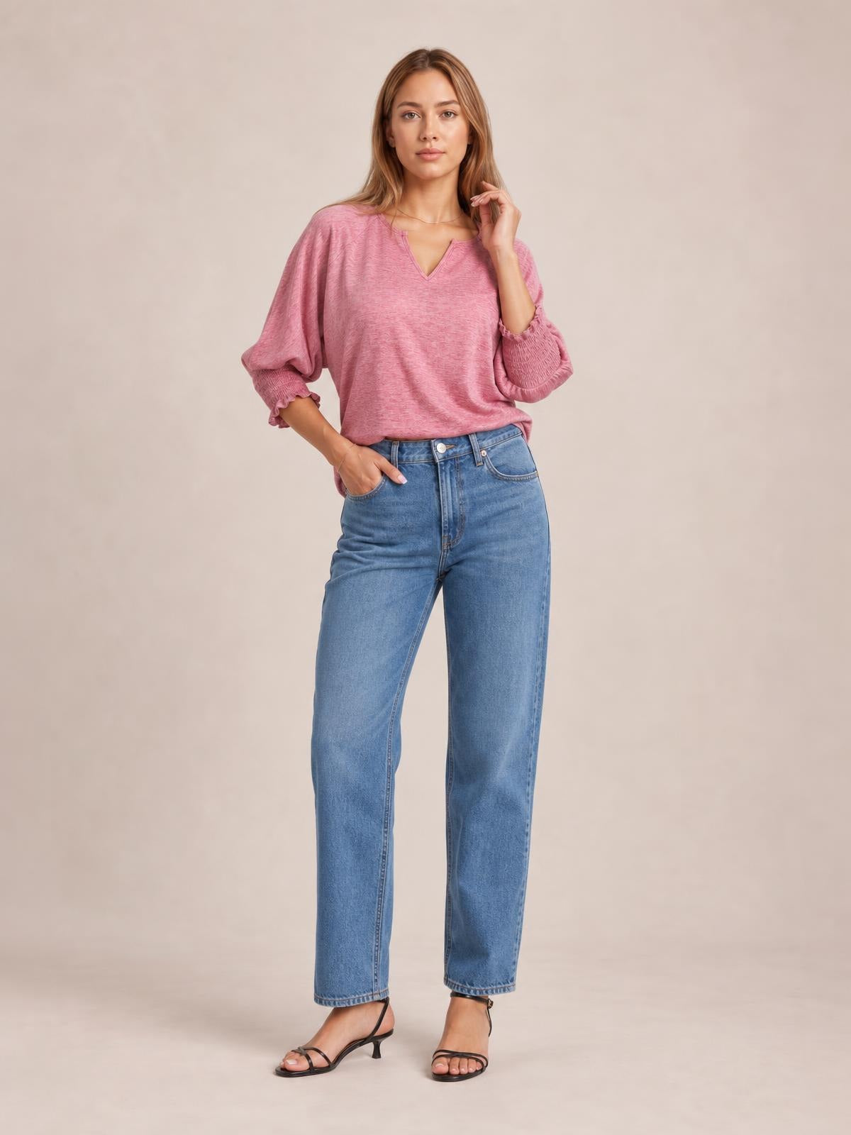 A model poses in a pink heathered blouse with a notched neckline, relaxed silhouette, voluminous lantern sleeves, and frilled gathered cuffs.