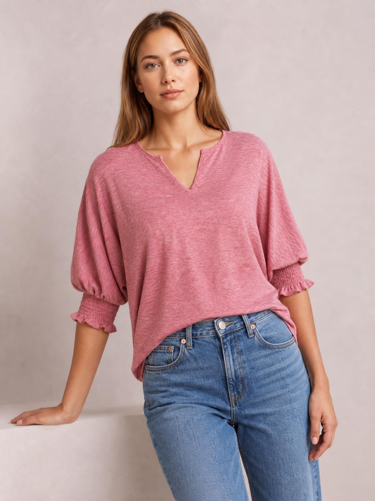 A model poses in a pink heathered blouse with a notched neckline, relaxed lantern sleeves, and frill-trimmed smocked cuffs.