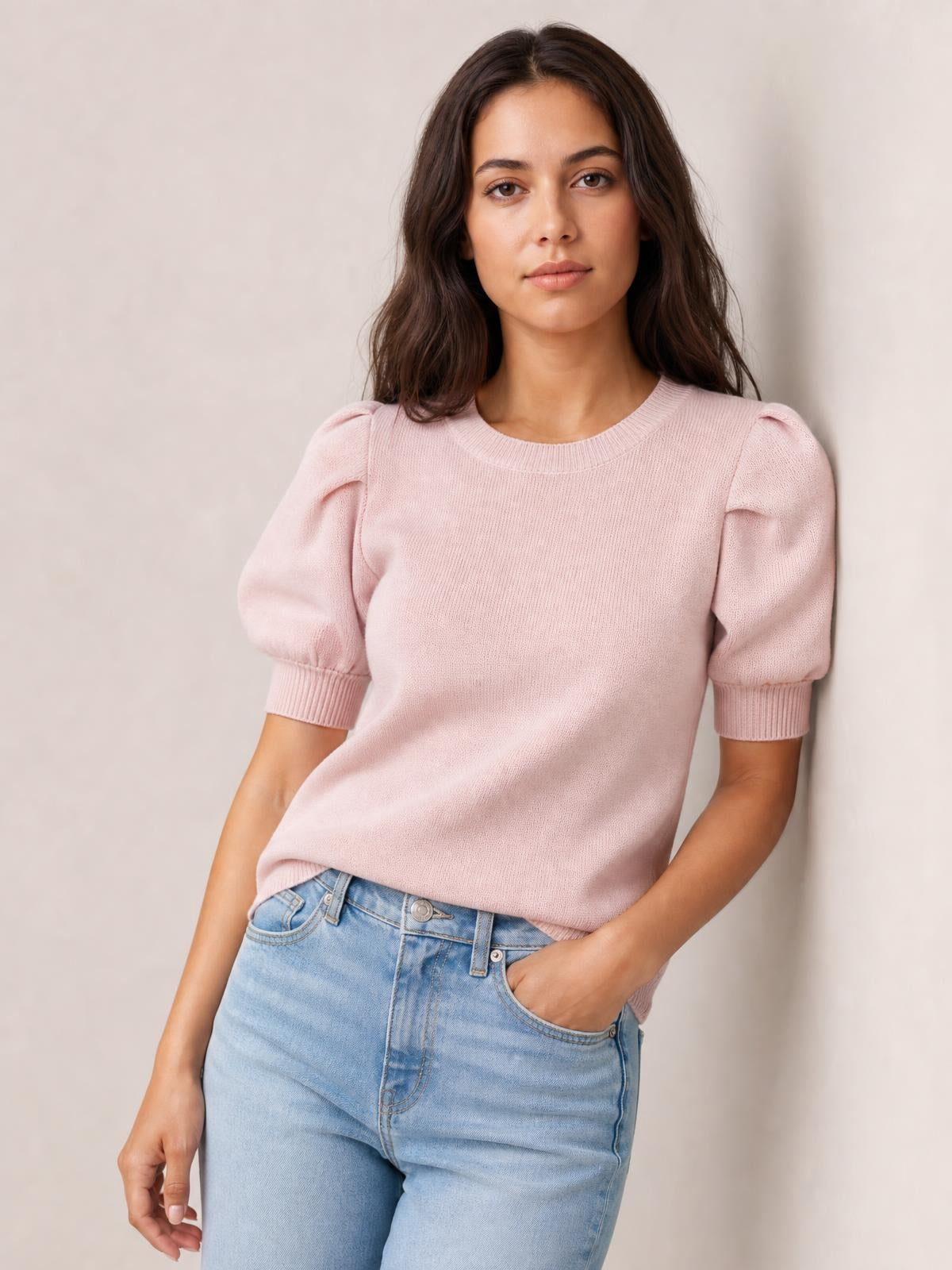 Model poses in a soft pink puff sleeve sweater with a ribbed neckline and cuffs, relaxed straight silhouette, and gently gathered short sleeves.