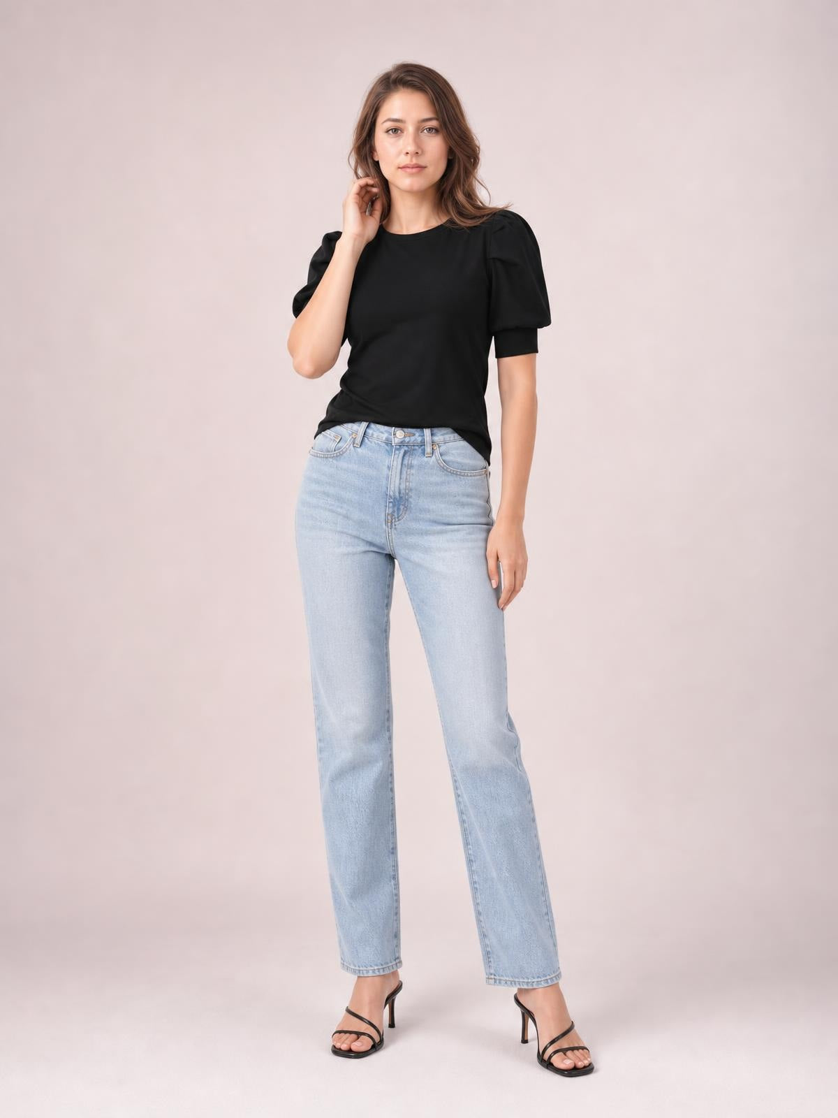 Model wears a black puff sleeve sweater with a simple fitted silhouette, short gathered sleeves, and a straight hem while posing with one hand near her hair.