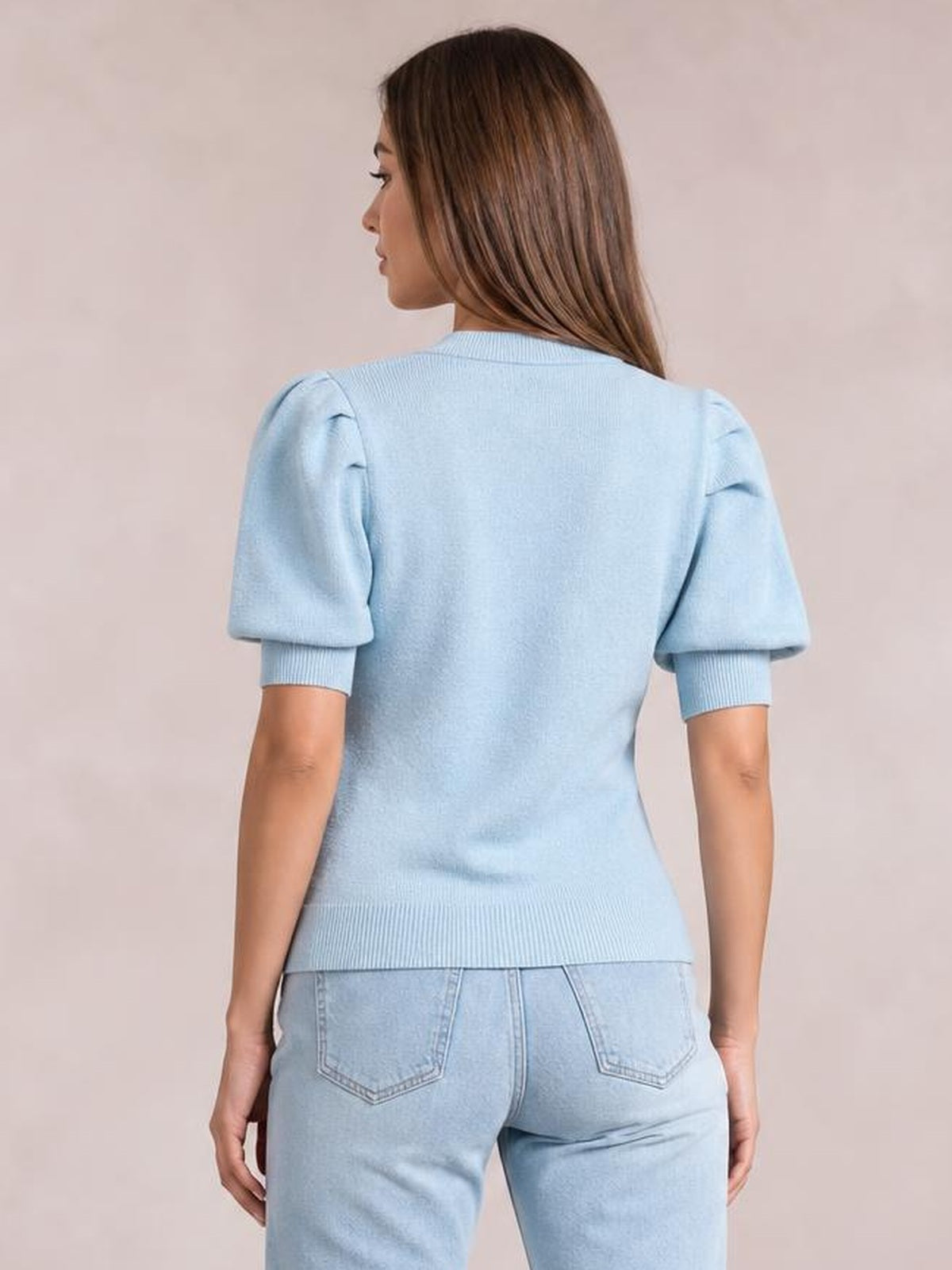 Model shown from the back wearing a light blue mock neck puff sleeve sweater with a fitted silhouette, ribbed cuffs, and hem.