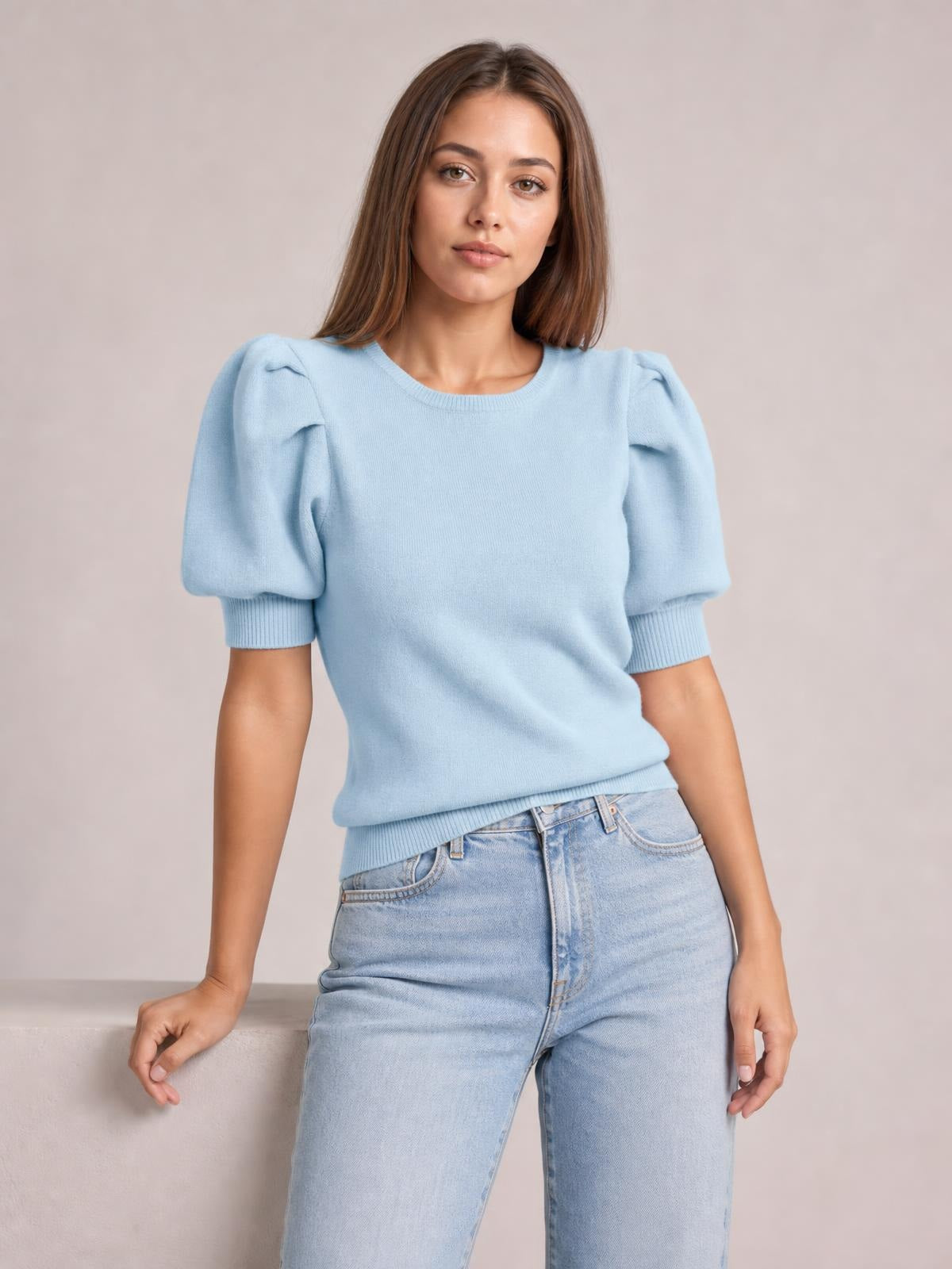 A model poses in a light blue puff sleeve sweater with short voluminous sleeves, ribbed cuffs and hem, and a relaxed straight silhouette.