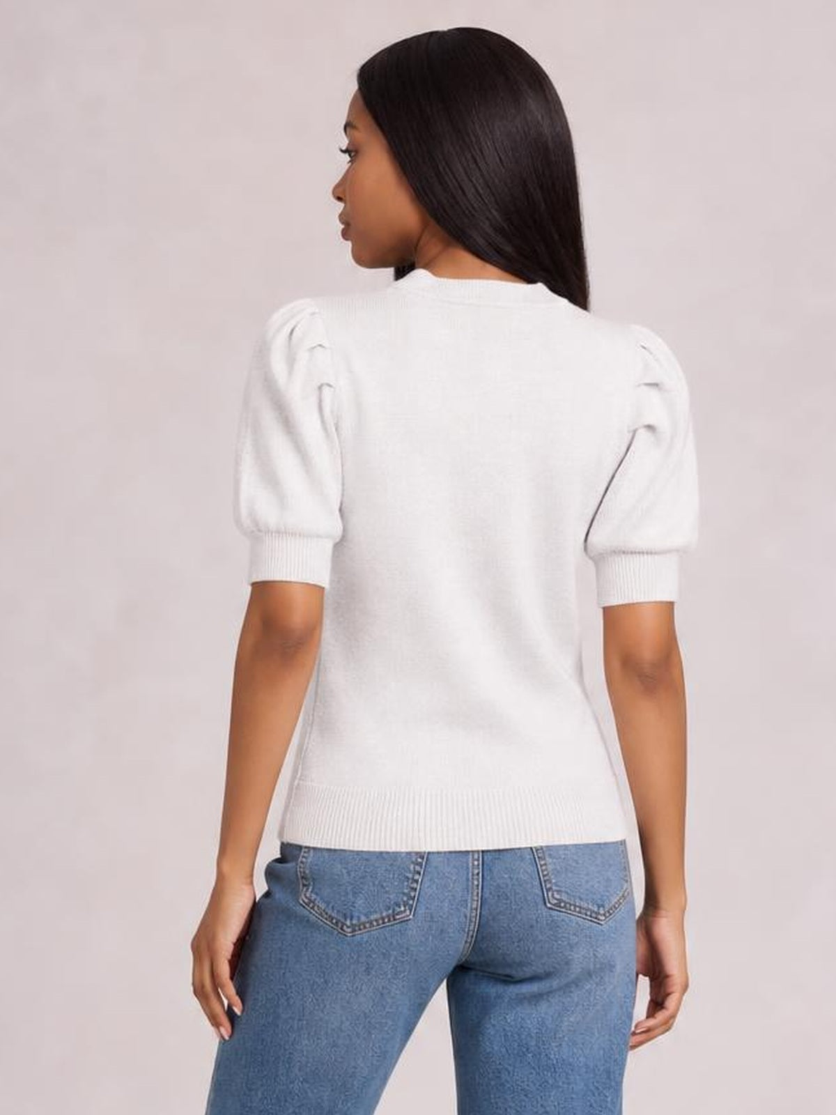 Model shown from the back wearing a white mock neck puff sleeve sweater with a relaxed silhouette, ribbed cuffs, and hem.