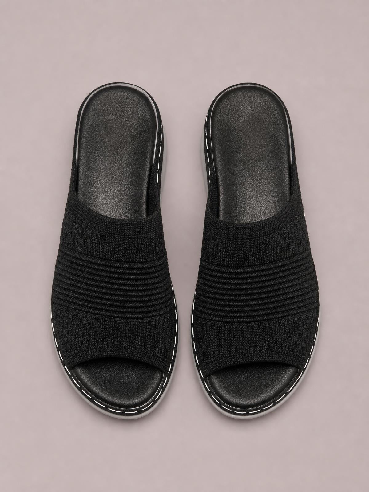 Black mesh open-toe flat sandals feature a rounded silhouette, layered ribbed upper bands, cushioned footbeds, and contrasting rubber soles.