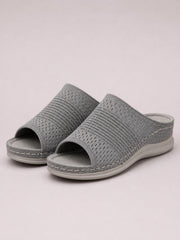 Gray mesh open-toe flat sandals feature wide woven slip-on uppers, cushioned footbeds, decorative stitching, and thick rubber soles.