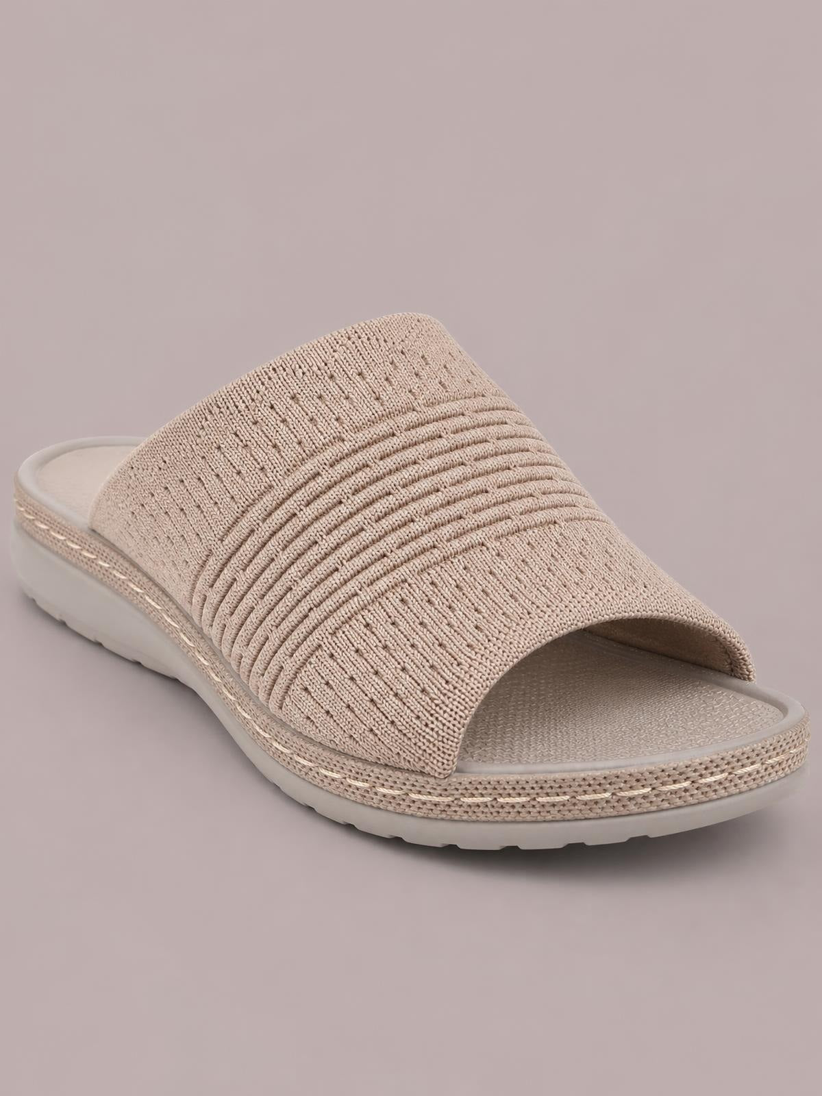 Beige mesh open-toe flat sandal with a wide textured woven upper, cushioned footbed, and flexible rubber sole.