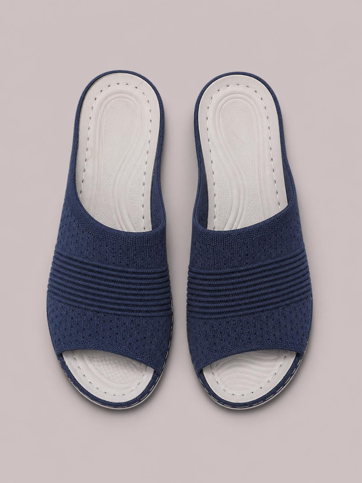 Navy mesh open-toe flat sandals feature wide textured straps, layered ruched bands, white contoured footbeds, and rubber soles in a top-down pair view.