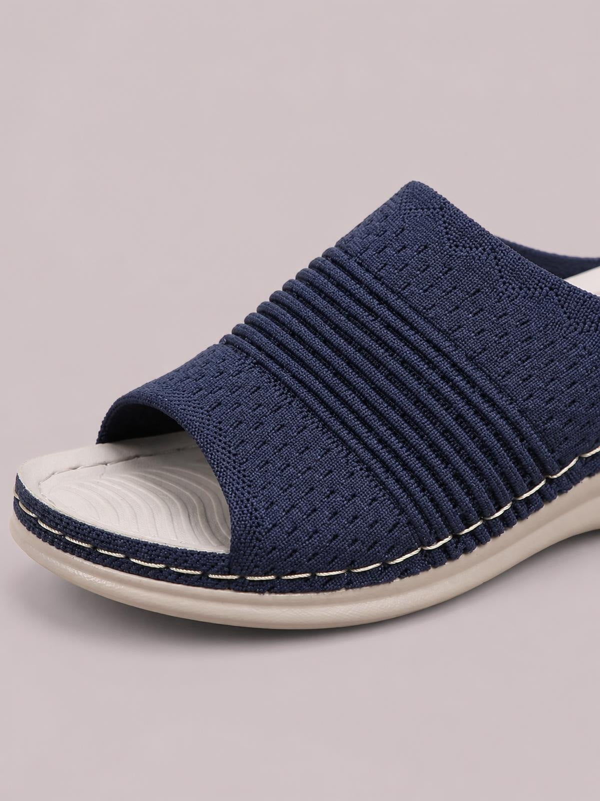 Navy mesh open-toe flat sandal with a wide textured upper, breathable construction, and a contrasting rubber sole.