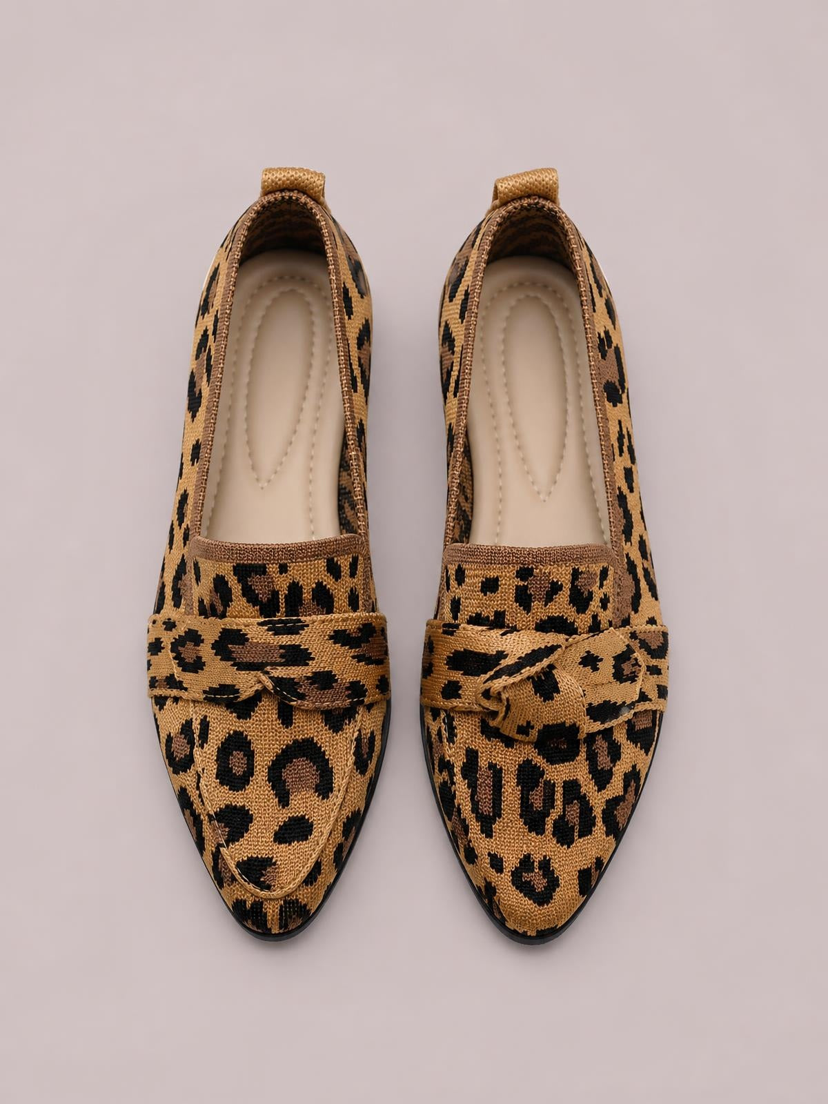Leopard-print mesh point-toe flat slip-ons feature a structured loafer silhouette, woven vamp bands with bow accents, cushioned insoles, and slim rubber soles.