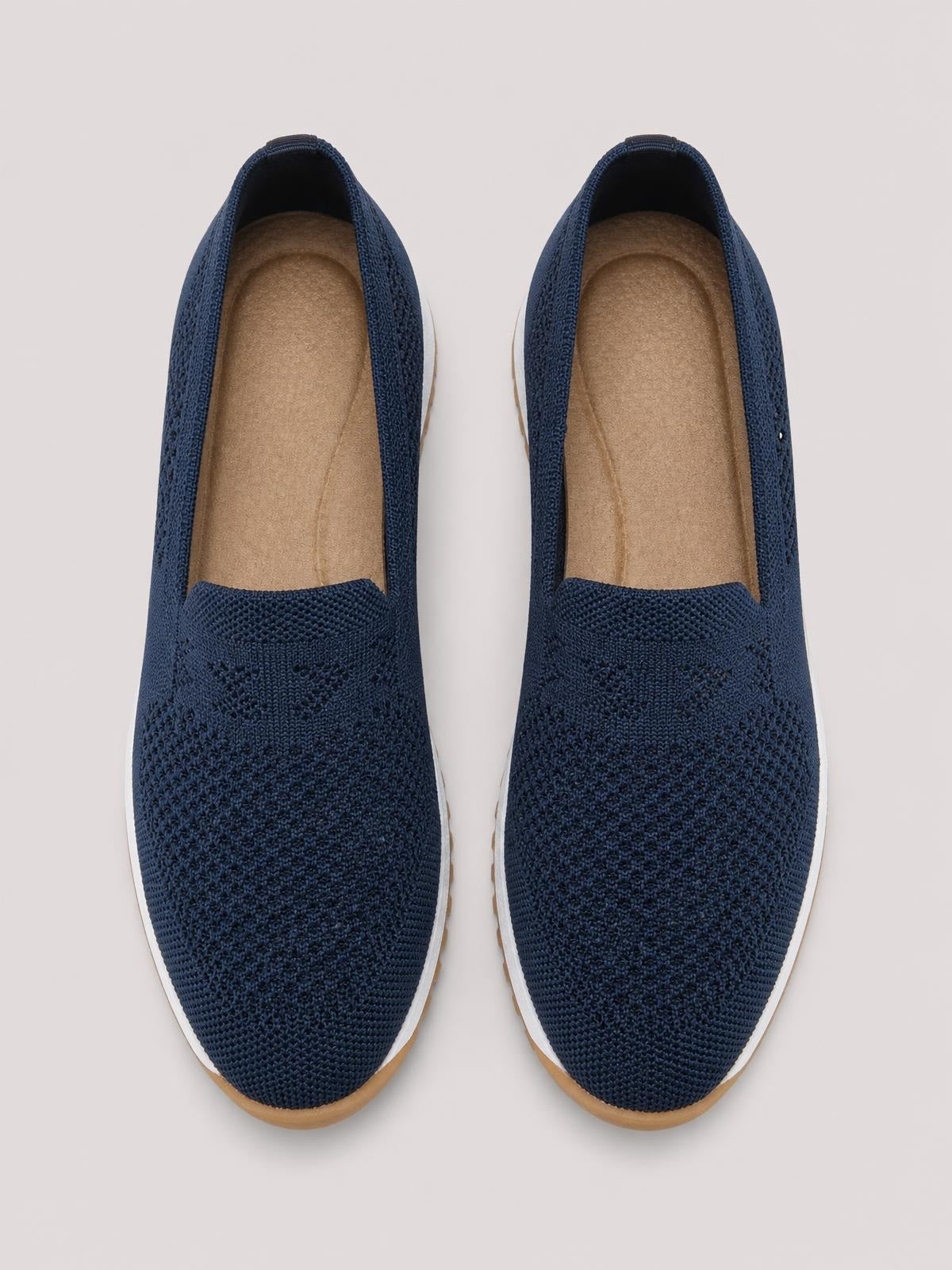 Navy mesh round-toe flat slip-ons feature a textured knit upper, open collar, tan footbed, and contrasting white rubber soles with gum-colored edges.