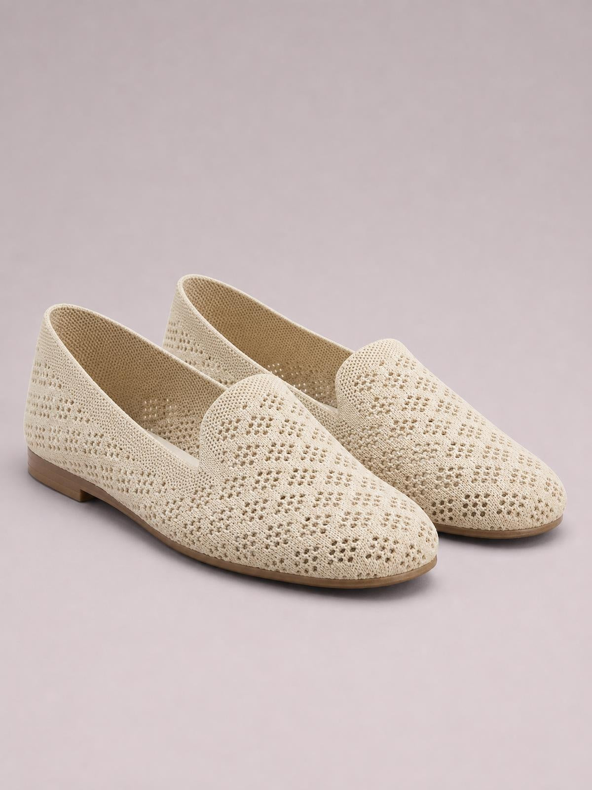 Cream mesh round-toe flat slip-on shoes feature perforated woven uppers, low rubber soles, and an easy open-back design.