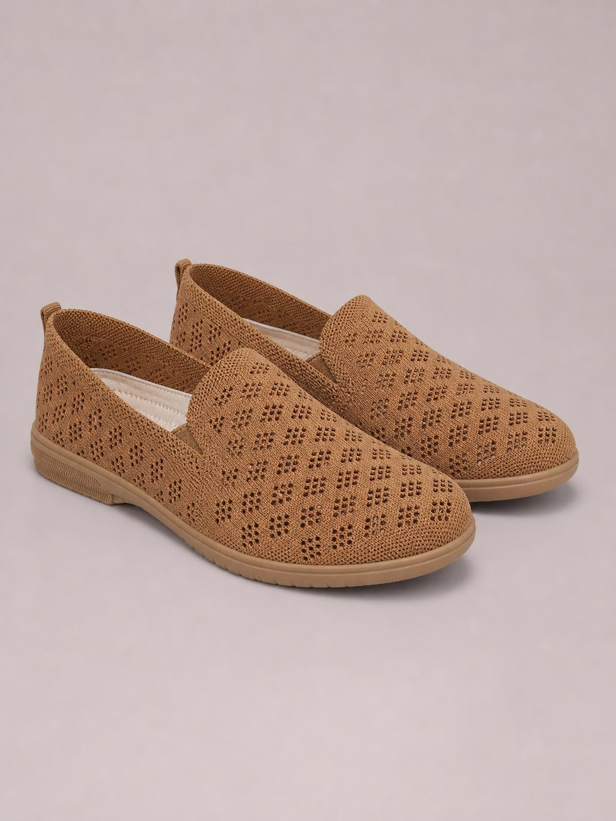 Tan mesh round toe flat slip-ons feature perforated detailing, elasticized openings, cushioned insoles, and textured rubber soles.