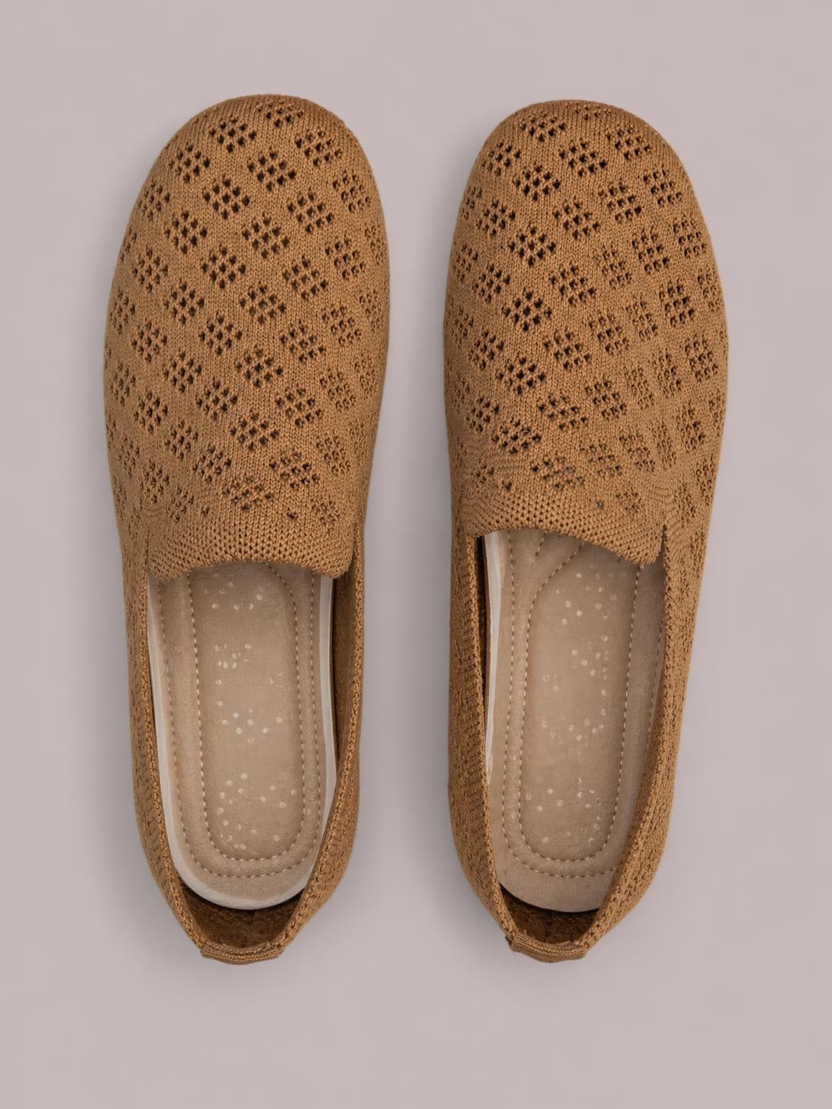 Top view of tan mesh round toe flat slip-ons with perforated knit uppers, open backs, cushioned insoles, and a simple low-profile silhouette.