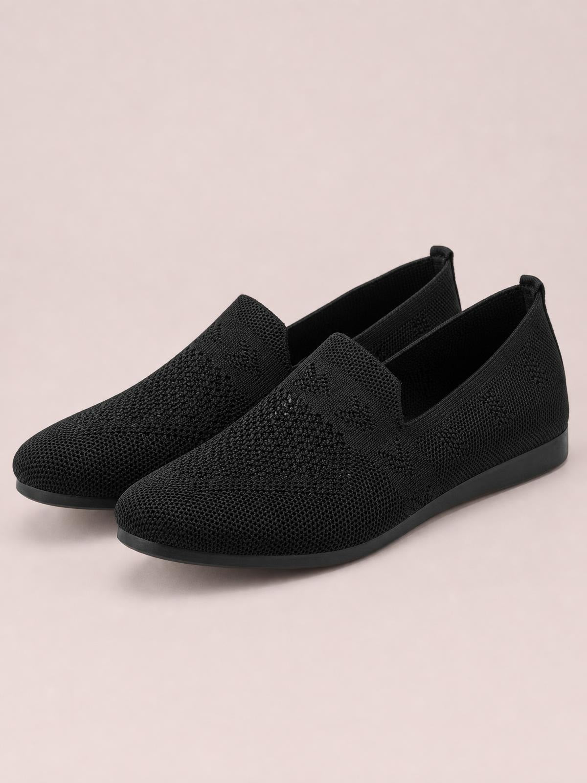 Black mesh round-toe flat slip-ons with low rubber soles, textured knit uppers, and streamlined pull-on openings.