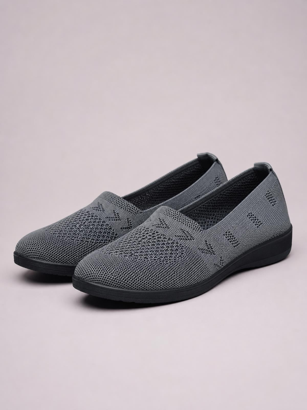 Gray mesh round-toe flat slip-ons feature a breathable patterned upper, elastic side panels, and a low-profile black rubber sole.