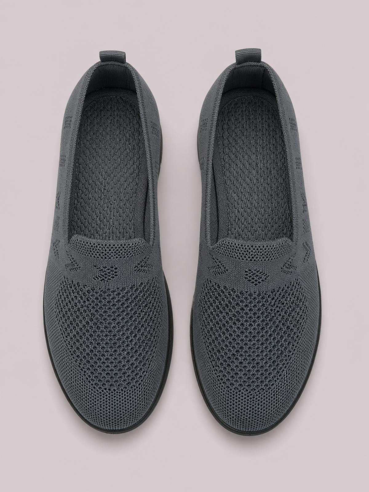 Dark gray mesh round toe flat slip-ons feature breathable knit construction, textured insoles, pull tabs, and low rubber soles.