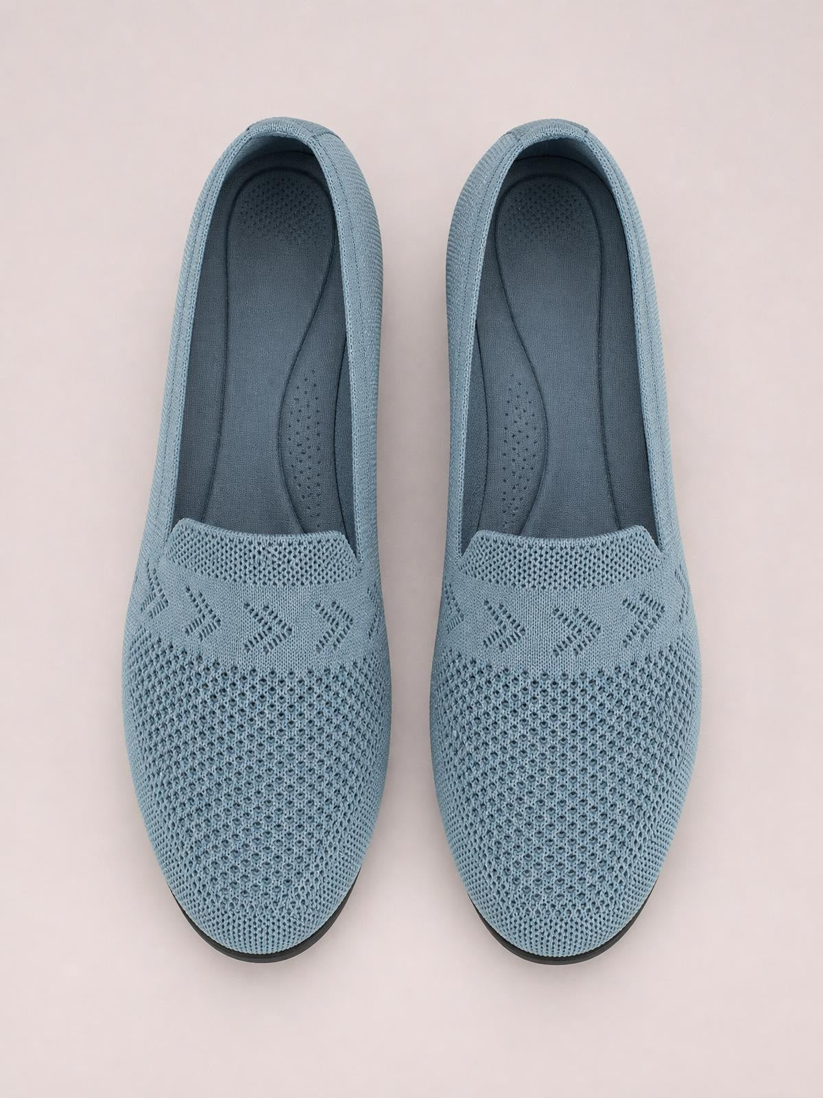 Light blue mesh round-toe flat slip-ons feature breathable knit uppers, patterned panels, cushioned insoles, and dark rubber outsoles.