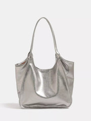 Metallic silver PU leather tote bag with a medium slouchy silhouette, long shoulder strap, open top, and neatly stitched curved seams.
